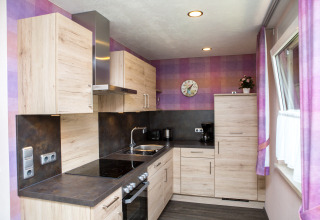 Moderne Glamping-Küche auf Camping en Vakantiepark Teichmann in Hessen mit Holzschränken und lila Wänden.