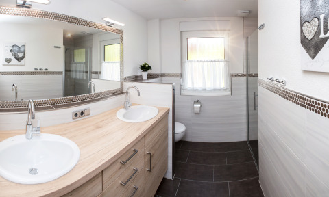 Moderne badeværelse med dobbelte håndvaske, spejl, toilet og bruser, set i glamping ved Teichmann.