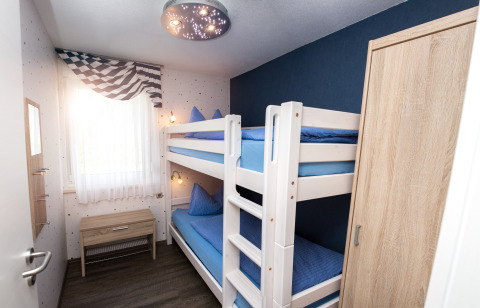 Chambre lumineuse avec lits superposés, meubles en bois et fenêtre dans un glamping à Hessen.