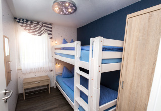 Hell eingerichtetes Zimmer mit Etagenbett, Schrank und Fenster in Glamping-Unterkunft Hessen, Deutschland.