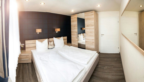 Modern bedroom with double bed and wooden furniture at Camping en Vakantiepark Teichmann glamping site.