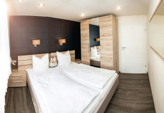 Habitación moderna con cama doble y muebles de madera en Camping en Vakantiepark Teichmann, glamping Hessen.