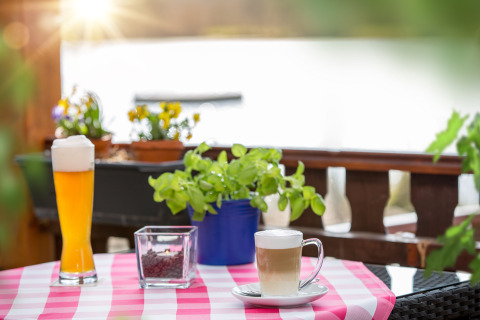 Vista di un tavolo all'aperto con birra, caffè, piante e fiori al Camping en Vakantiepark Teichmann - Glamping Hessen.