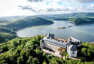 Vista aérea de un castillo junto al lago y colinas verdes, perfecto para glamping en Camping Teichmann, Hessen.