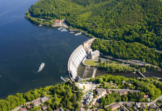 Vista aérea de Camping en Vakantiepark Teichmann - Glamping Hessen junto a un lago y presa rodeados de bosque.