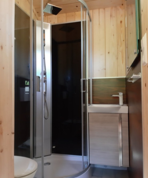 Salle de bain moderne en bois avec douche et lavabo, dans un hébergement Gallushof glamping, Bade-Wurtemberg.