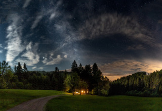 Cielo stellato sul glamping Gallushof nella campagna del Baden-Württemberg, con baita illuminata nel bosco.