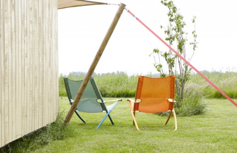 Two colorful camping chairs on grass next to a wooden cabin at It Dreamlân - Ecolodges Friesland.