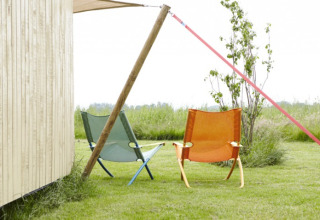 Deux chaises de camping colorées sur l’herbe à côté d’une cabane chez It Dreamlân - Ecolodges Friesland.