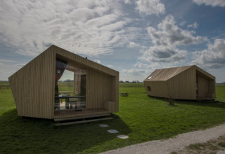 To moderne træhytter på grøn mark under en skyet himmel, It Dreamlân - Ecolodges Friesland, glamping.