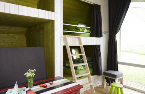 Interno di un alloggio glamping con letti a castello, pareti in legno e ampie finestre a It Dreamlân Friesland.