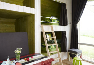 Interieur van glampingaccommodatie met stapelbedden, houten wanden en grote ramen bij It Dreamlân Friesland.