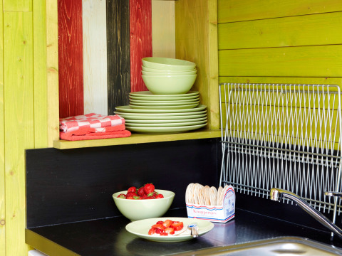 Zona de cocina en It Dreamlân - Ecolodges Friesland con platos verdes, fresas y escurridor de platos.