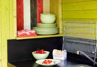 Coin cuisine d’It Dreamlân - Ecolodges Friesland avec assiettes vertes, fraises et égouttoir à vaisselle.