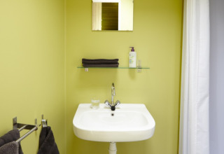 Baño en It Dreamlân - Ecolodges Friesland con lavabo, toallas, espejo y estante, destacado en camping glamping.