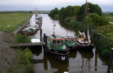 Boten aangemeerd aan een smal kanaal met groene omgeving bij It Dreamlân - Ecolodges Friesland in Nederland.