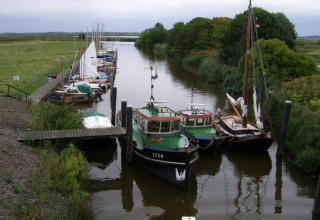 Barcos atracados en un canal rodeado de vegetación cerca de It Dreamlân - Ecolodges Friesland en Holanda.