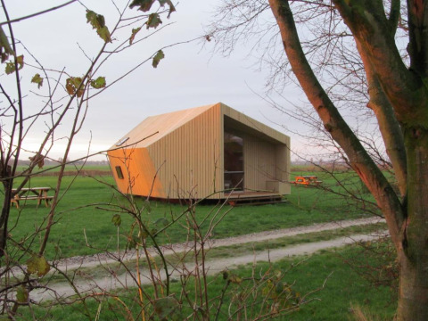 Modernes, hölzernes Glamping-Haus bei It Dreamlân - Ecolodges Friesland auf grüner Wiese unter freiem Himmel.
