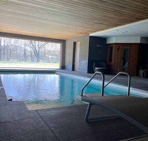 Binnenzwembad met groot raam bij Glamping Goed Van Den Bogaerde in West-Vlaanderen, België.