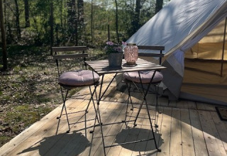 Udendørs træterrasse med bord og stole foran et glampingtelt hos Glamping Goed Van Den Bogaerde.