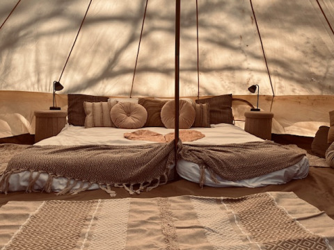 Innenansicht eines Glamping-Zeltes bei Glamping Goed Van Den Bogaerde mit gemütlichem Bett in Braun.