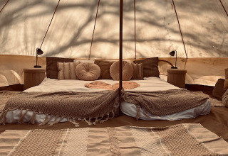 Interior of a glamping tent at Glamping Goed Van Den Bogaerde with cozy bed and neutral earth tones.