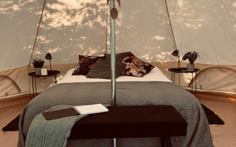 Luxe glamping-accommodatie met comfortabel bed en sfeervolle inrichting in West-Vlaanderen, België.