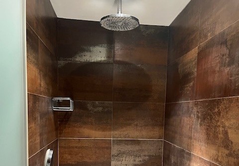 Douche avec pommeau effet pluie et carrelage brun au Glamping Goed Van Den Bogaerde en Flandre-Occidentale.