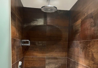 Brusebad med regnbruser og brune fliser i Glamping Goed Van Den Bogaerde, Glamping i West-Vlaanderen.