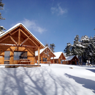 Gemütliche Holzhütten im Schnee bei den Huttopia Winter Chalets – Font Romeu, Glamping Pyrenäen.