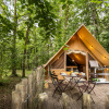 Cozy glamping tent in a lush forest setting with outdoor dining at Village Huttopia Lanmary-Périgord in Dordogne.