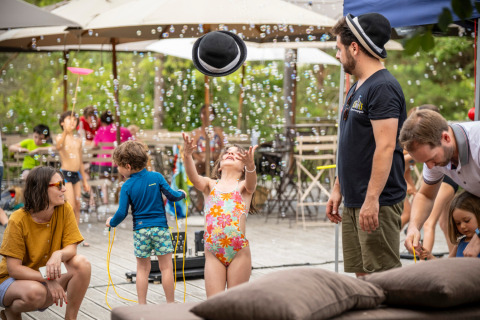 Bambini giocano con le bolle mentre gli adulti si rilassano a Village Huttopia Lanmary-Périgord in Dordogne.