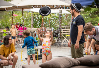 Children play with bubbles as adults relax on the terrace at Village Huttopia Lanmary-Périgord in Dordogne.