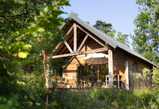 Houten hut omgeven door natuur bij Village Huttopia Lanmary-Périgord – Glamping Dordogne, ideaal voor rustzoekers.