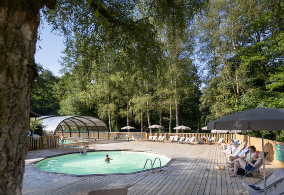 Udendørs poolområde omgivet af træer hos Huttopia Vallée de la Semois glamping i Ardennerne, Wallonien.