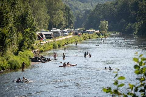 Campeggio sul fiume a Huttopia Vallée de la Semois, Ardenne, con persone che nuotano e si rilassano.