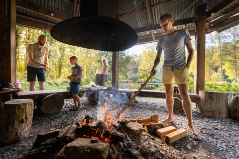 Gezin rond het kampvuur bij Huttopia Vallée de la Semois, glamping midden in de Waalse Ardennen.