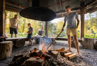 Family enjoys time around a campfire at Huttopia Vallée de la Semois glamping site in the Ardennes forest.