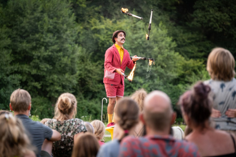 Artiste jongle avec des torches enflammées devant un public à Huttopia Vallée de la Semois en Ardenne.