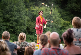 Artiste jongle avec des torches enflammées devant un public à Huttopia Vallée de la Semois en Ardenne.