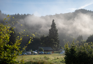 Glamping at Huttopia Vallée de la Semois in the Ardennes with tents and mist over a forest valley.