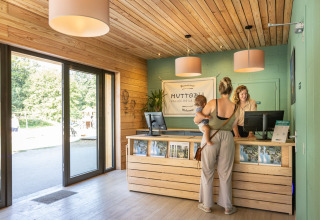Reception af Huttopia Vallée de la Semois glamping i Ardennerne med gæst og barn ved indtjekning.