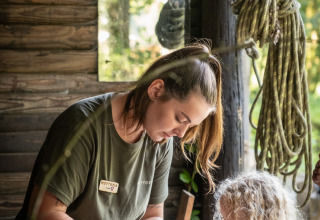 A woman and a child doing crafts together inside a rustic cabin at Huttopia Vallée de la Semois.