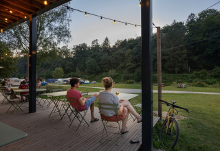 Mensen genieten op het terras bij Huttopia Vallée de la Semois glamping in de Ardennen, Wallonië.