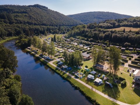 Luftaufnahme von Huttopia Vallée de la Semois, einem Glampingplatz an einem Fluss in den Ardennen.