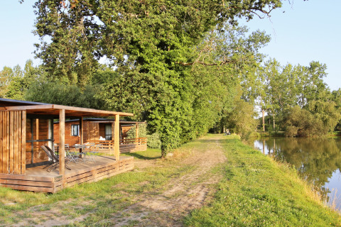Alloggi glamping in legno sul lago presso Huttopia Baie du Mont Saint Michel, immersi nella natura.