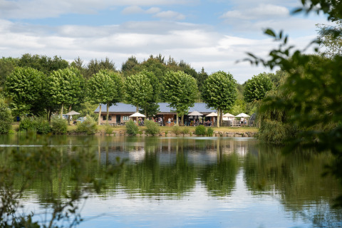 Alloggio glamping Huttopia Baie du Mont Saint Michel sul lago, circondato da alberi e natura verde.