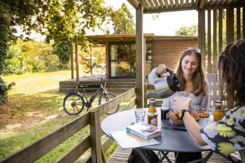Zwei Personen frühstücken im Freien bei Huttopia Baie du Mont Saint Michel, Glamping Bretagne.