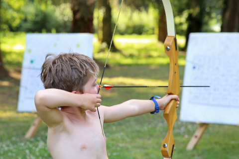Boy practicing archery outdoors at Huttopia Baie du Mont Saint Michel – Glamping Bretagne campsite.