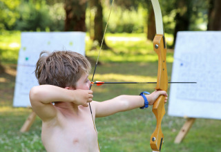 Junge übt Bogenschießen im Freien bei Huttopia Baie du Mont Saint Michel – Glamping Bretagne.